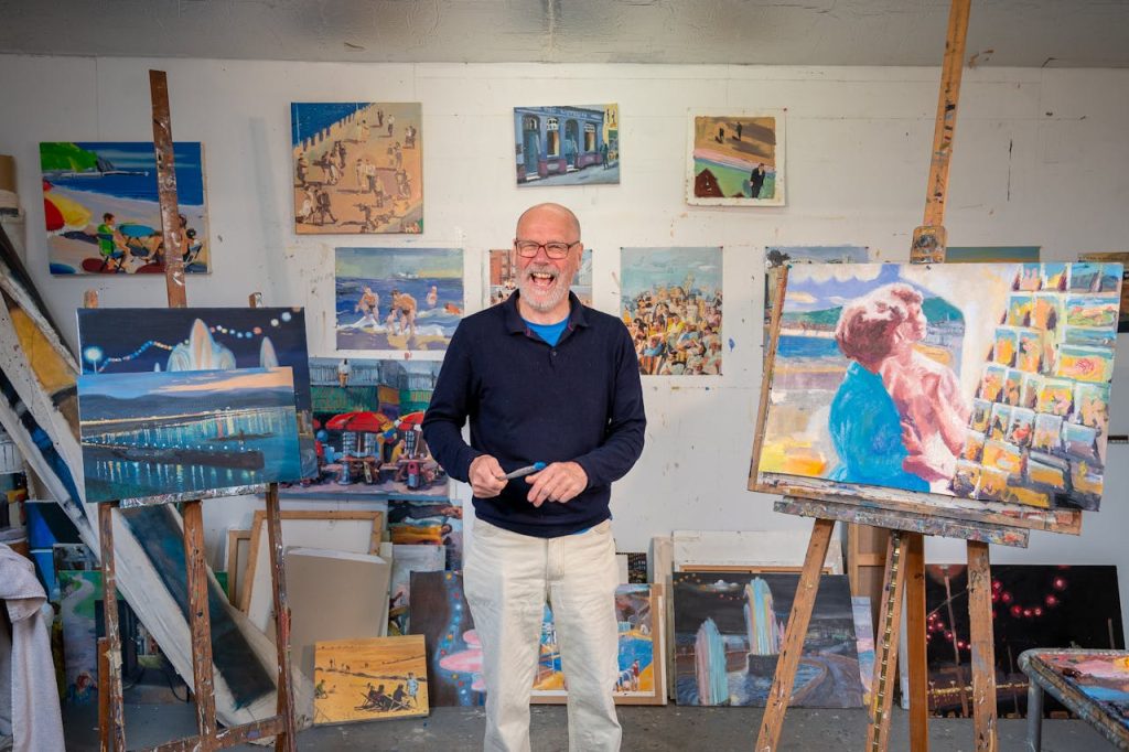 Happy artist standing with his latest collection of paintings.
